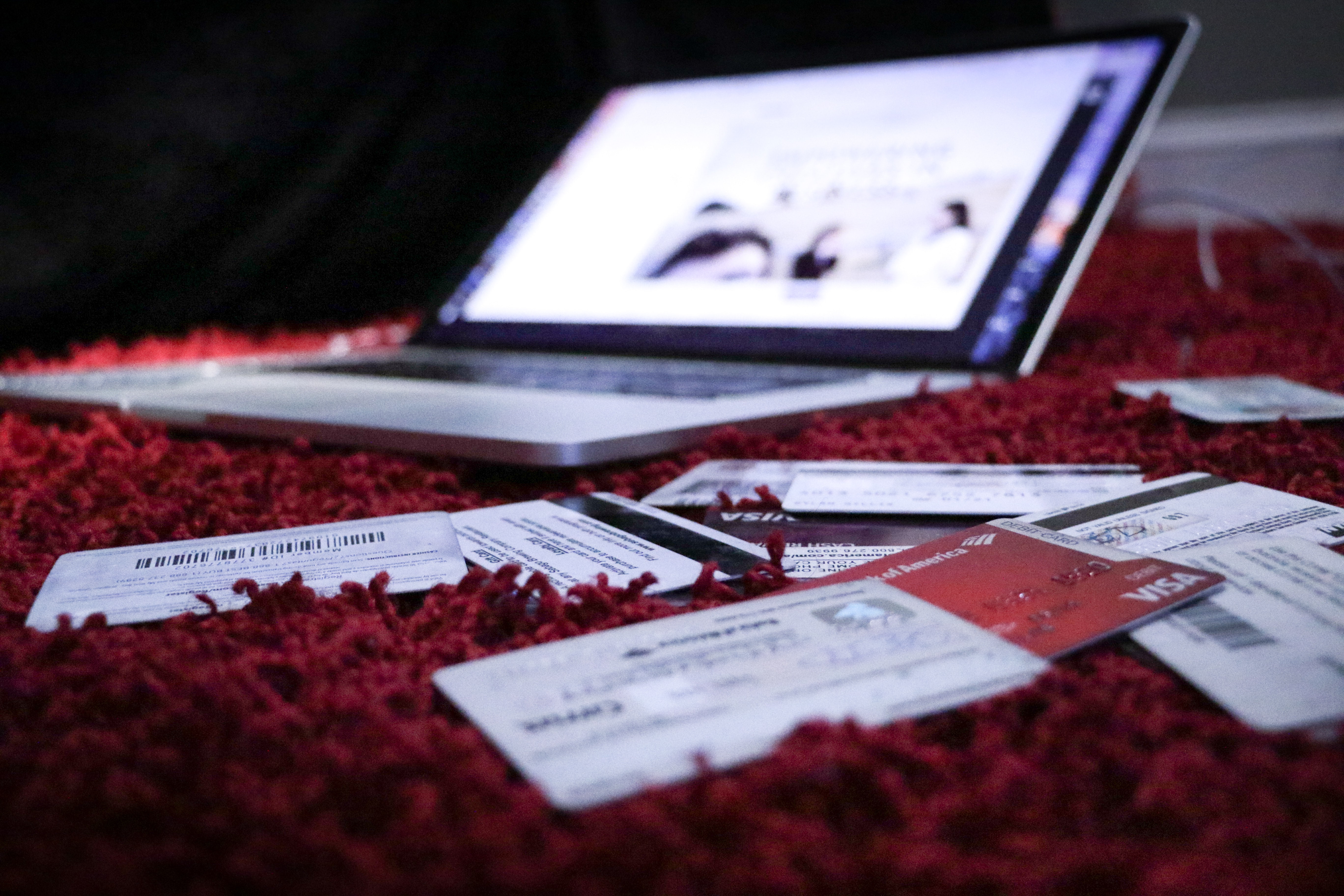 a laptop on a red carpet with credit cards surrounding it